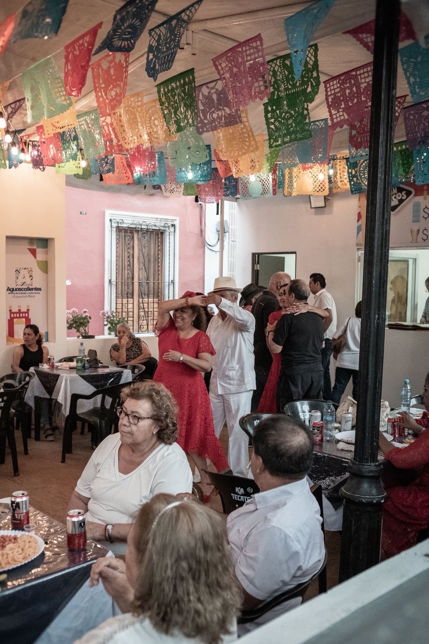Stock photograph of multiple generations dancing beneath colorful papel picado